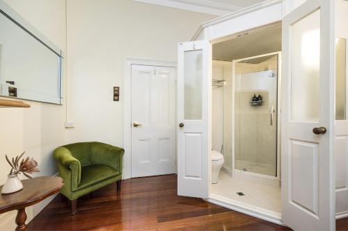 y baño con silla verde y ducha. en Crepe Myrtle Cottage, en South Fremantle