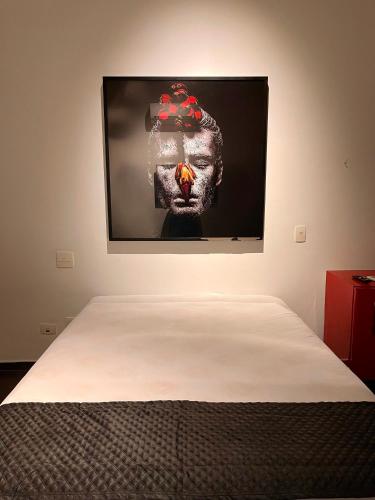 a bed in a room with a picture on the wall at Acomodações do Tio Will - 2 in Guarujá