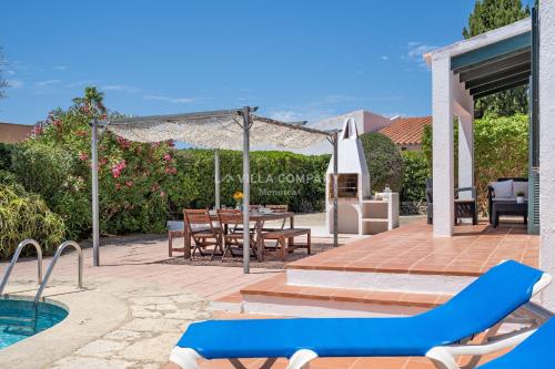 un patio con tavolo, sedie e piscina di Villa BINIKIXA a Binibeca