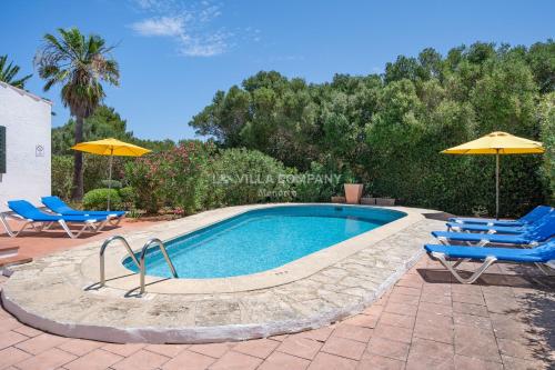 a swimming pool with two chairs and two umbrellas at Villa BINIKIXA in Binibeca