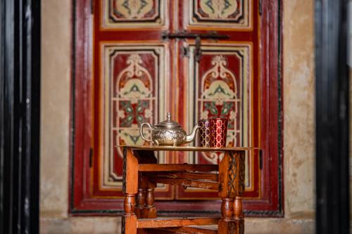 uma mesa com um bule de chá e chávenas na frente de uma porta em Riad Le Jardin de Lea, Suites & Spa em Marraquexe