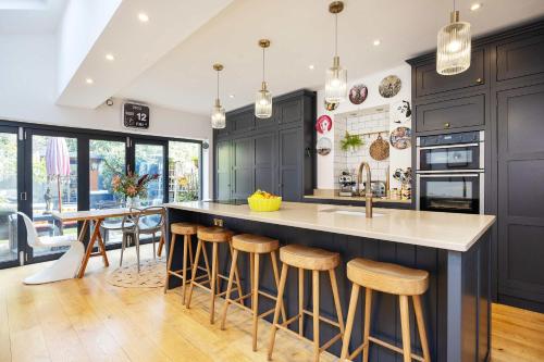a kitchen with black cabinets and a island with bar stools at Veeve - Soulful Smiles in London