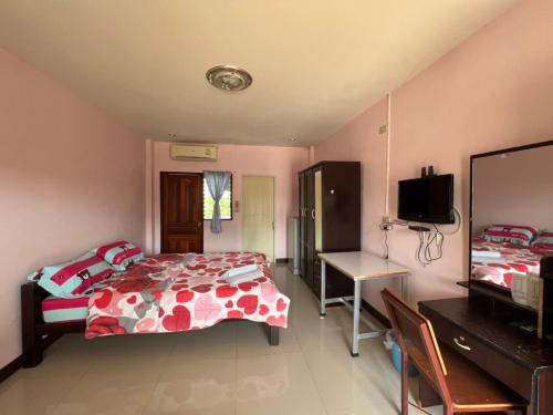 een slaapkamer met 2 bedden, een bureau en een televisie bij ที่พักสกลนคร กิตติวัฒน์อพาร์ทเม้นท์&รีสอร์ท in Sakon Nakhon