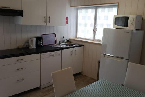 W kuchni znajduje się biała lodówka i kuchenka mikrofalowa. w obiekcie Le Chai Rit w mieście Rivedoux-Plage