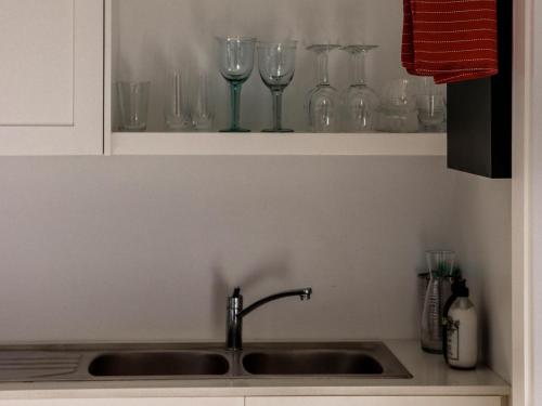 a sink in a kitchen with glasses on a shelf at The Beach Bungalow in Hermanus
