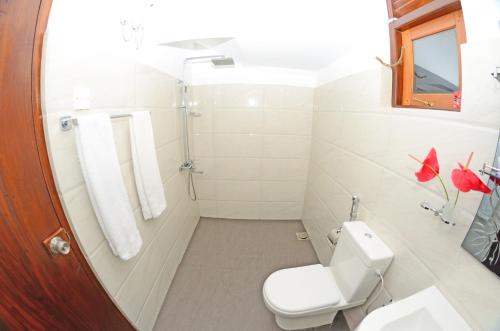 a white bathroom with a toilet and a shower at Sethum Villa Plus in Unawatuna
