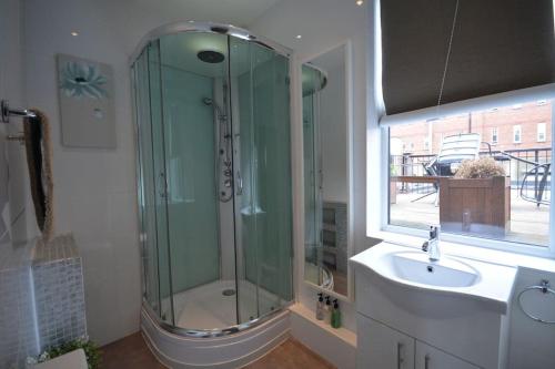 La salle de bains est pourvue d'une douche, d'un lavabo et d'une fenêtre. dans l'établissement Cheerful 2 bed home with terrace in central Camden, à Londres