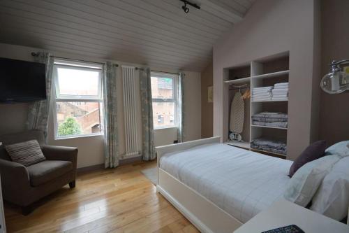 a bedroom with a large white bed and a chair at Cheerful 2 bed home with terrace in central Camden in London