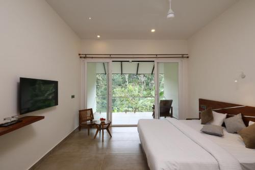 Spice Forest Plantation Homestay, Thekkady في Vandiperiyār: غرفة نوم بسرير كبير ونافذة كبيرة