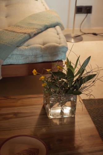 a glass vase with flowers on a table next to a bed at Eraeliya Villas & Gardens in Weligama