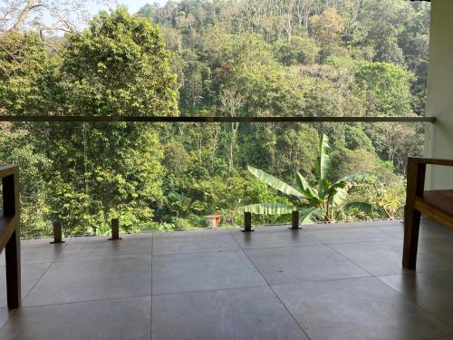 a large balcony with a view of a forest at Spice Forest Plantation Homestay, Thekkady in Vandiperiyār