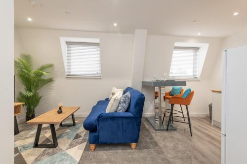 a living room with a blue chair and a table at Thornhill House by Guestz in Wakefield