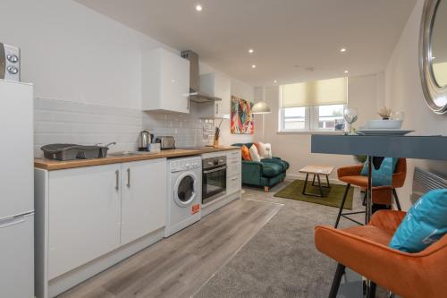 a kitchen with a washing machine and a living room at Thornhill House by Guestz in Wakefield