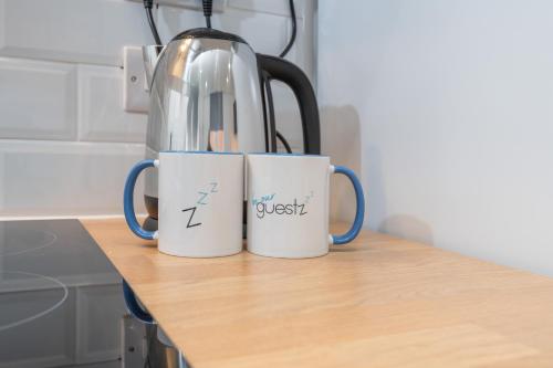 two mugs sitting on top of a kitchen counter at Thornhill House by Guestz in Wakefield