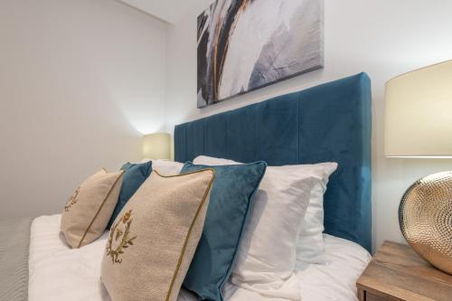 a bedroom with a blue headboard and pillows on a bed at Thornhill House by Guestz in Wakefield
