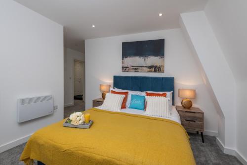 a bedroom with a large bed with a yellow blanket at Thornhill House Serviced Apartments in Wakefield