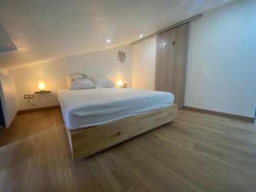 ein Schlafzimmer mit einem Bett mit weißer Bettwäsche und zwei Lampen in der Unterkunft Maison au pied du château + parking privé in Champeix