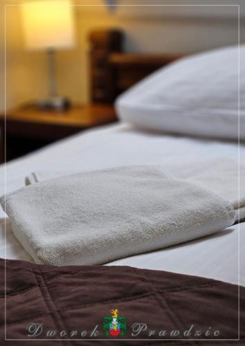 two white beds with a towel on top of them at Dworek Prawdzic Niechorze in Niechorze