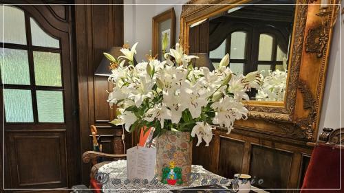 un jarrón de flores blancas en una mesa frente a un espejo en Dworek Prawdzic Niechorze, en Niechorze