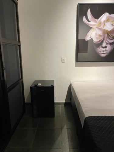 a bedroom with a bed and a flower on the wall at Acomodações do Tio Will - 2 in Guarujá