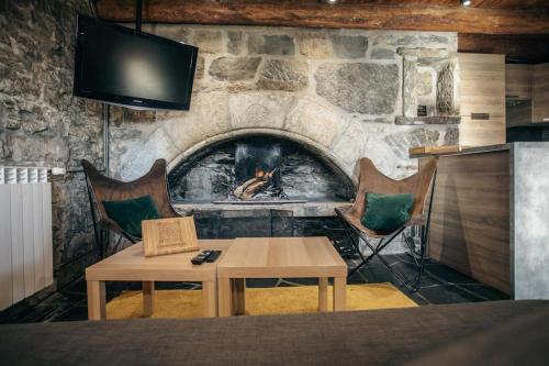 a room with a stone fireplace with a table and chairs at La grange du hameau in Saint-Lary-Soulan