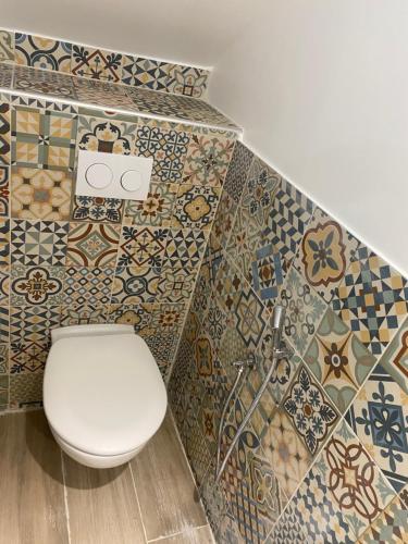a bathroom with a toilet and tiles on the wall at Villa Houria in Gonesse