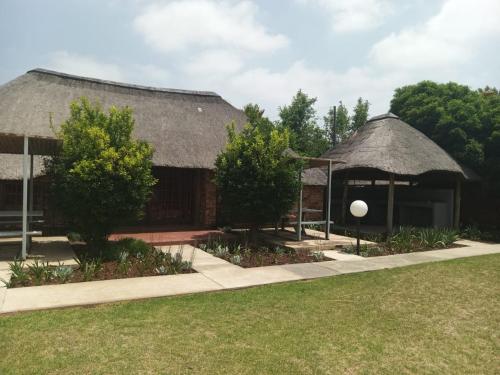 a building with a thatched roof and a garden at Pepe Piatto Lodge in Grootvlei