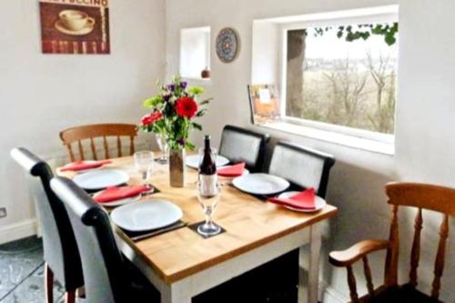 a dining room table with a bottle of wine and chairs at Cosy 3 Bed Cottage near 3 Peaks - Log Burner & Aga in High Bentham