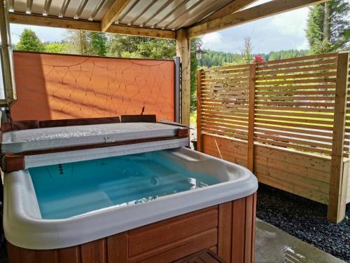 a hot tub in a backyard with a pergola at Glenariff Forest Getaway in Glenariff