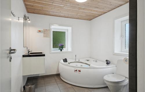 baño blanco con bañera y aseo en Beautiful Home In Snder Omme With 7 Bedrooms, Wifi And Jacuzzi, en Sønder Omme