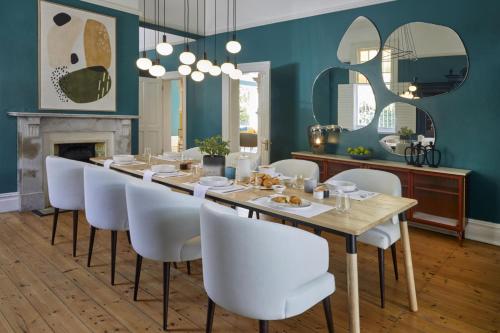uma sala de jantar com uma mesa longa e cadeiras brancas em More Quarters Hotel em Cidade do Cabo
