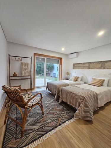 um quarto com duas camas e uma cadeira. em ON THE WAY - Mindelo Beach/Guest House em Mindelo
