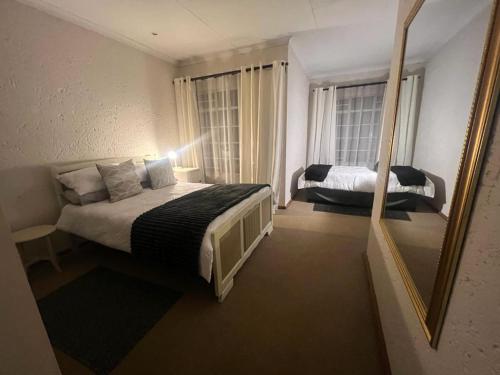 a bedroom with a large bed and a mirror at Die Eend in Centurion