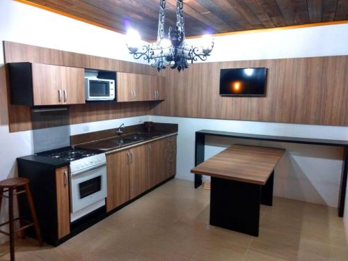 a kitchen with wooden cabinets and a table and a chandelier at Hotel Sambura in Imbé