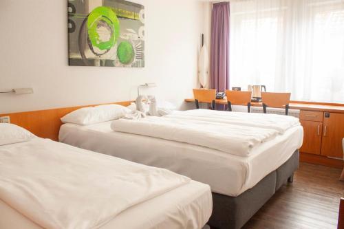 a hotel room with two beds and a table at hogh Hotel Heilbronn in Heilbronn