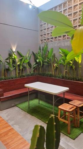 una mesa blanca y un banco en una habitación con plantas en Emerald Guest House London Purwokerto en Purwokerto
