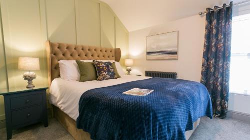 a bedroom with a large bed with a blue blanket at 9 Rose Hill in Beaumaris