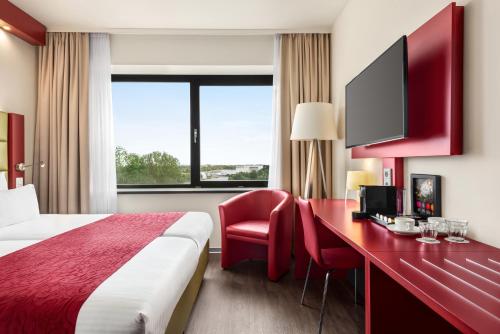 a hotel room with a bed and a desk with a tv at Amedia Amsterdam Airport Schiphol, Trademark Collection by Wyndham in Schiphol