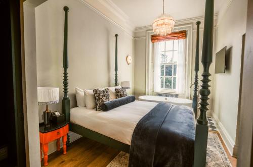 a bedroom with a four poster bed and a bath tub at Hunton Park Hotel in Kings Langley