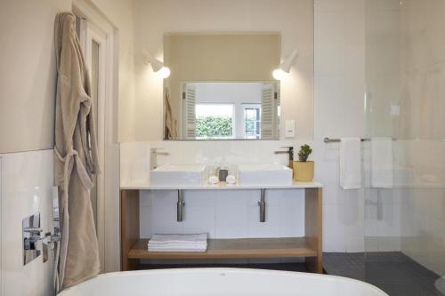 La salle de bains est pourvue d'un lavabo et d'un miroir. dans l'établissement More Quarters Hotel, au Cap