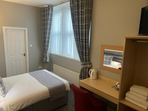 a bedroom with a bed and a desk and a window at Holborn Hotel in Thurso