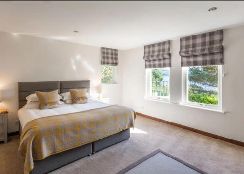 a bedroom with a bed and two windows at Loch Ness Cottages in Brackla