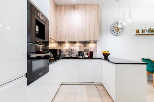 Una cocina con gabinetes blancos y electrodomésticos negros. en Marina Ilavia - przy jeziorze, ogródek, garaż podziemny, winda, klimatyzacja, 2xTV z Netflix, en Iława