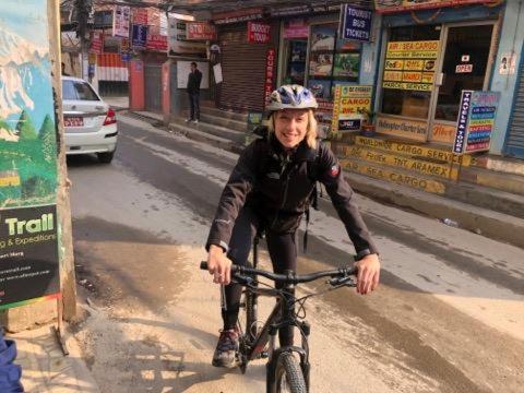 una mujer montando una bicicleta por una calle en Hotel Nagarjun Palace en Katmandú