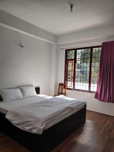 - une chambre avec un grand lit et 2 fenêtres dans l'établissement Pinewood guesthouse, à Tawang
