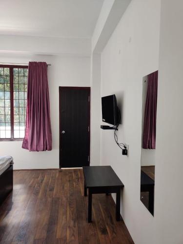 - un salon avec une table et une télévision dans l'établissement Pinewood guesthouse, à Tawang