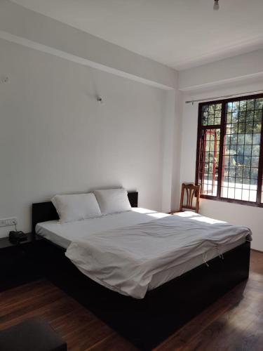 - une chambre avec un grand lit et des draps blancs dans l'établissement Pinewood guesthouse, à Tawang