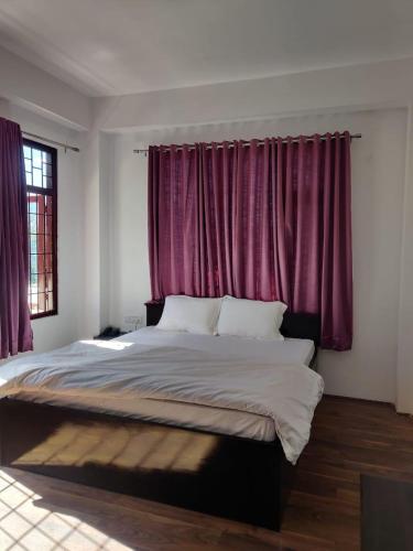 - une chambre avec un grand lit et des rideaux violets dans l'établissement Pinewood guesthouse, à Tawang