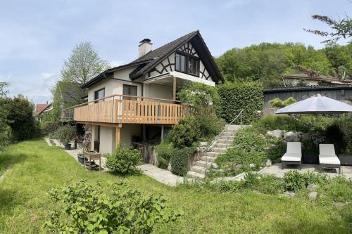 a house with a deck and an umbrella in the yard at Wohlfühl-Haus mit Panoramablick in Oberneuforn