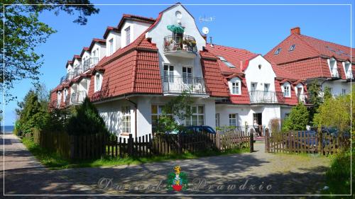 une grande maison blanche avec un toit rouge dans l'établissement Dworek Prawdzic Niechorze, à Niechorze